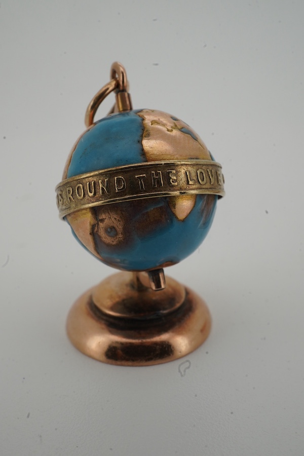 A yellow metal and enamel globe charm, reading 'The whole world turns round the love', height 3.2cm; and a gold and amber pendant, length 4.5cm, Russian assay marks for 14ct gold